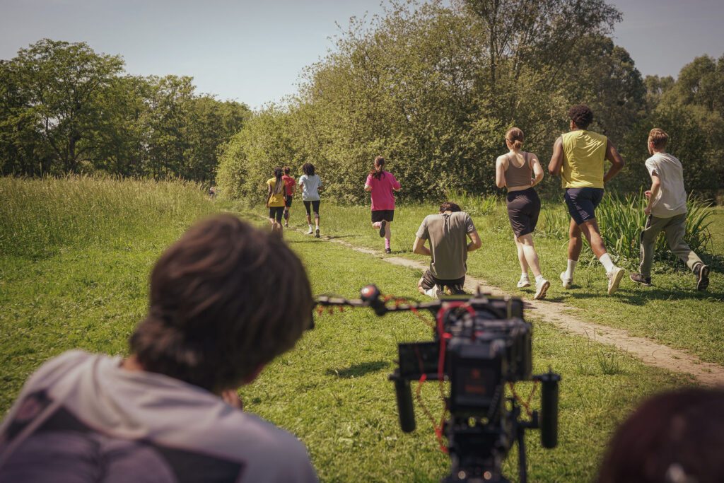 L'équipe de tournage traverse une prairie avec la caméra et le matériel