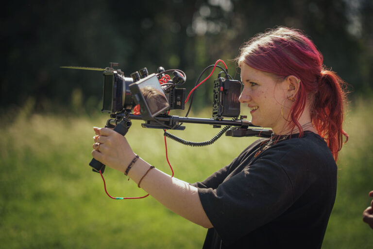 Une cadreuse filme en extérieur, caméra en main